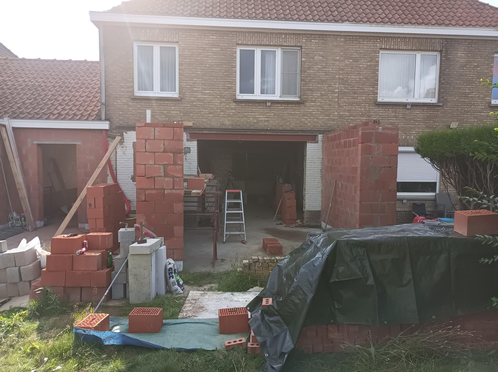 Achtergevel met oude bruine baksteen en open garage vóór totaalrenovatie