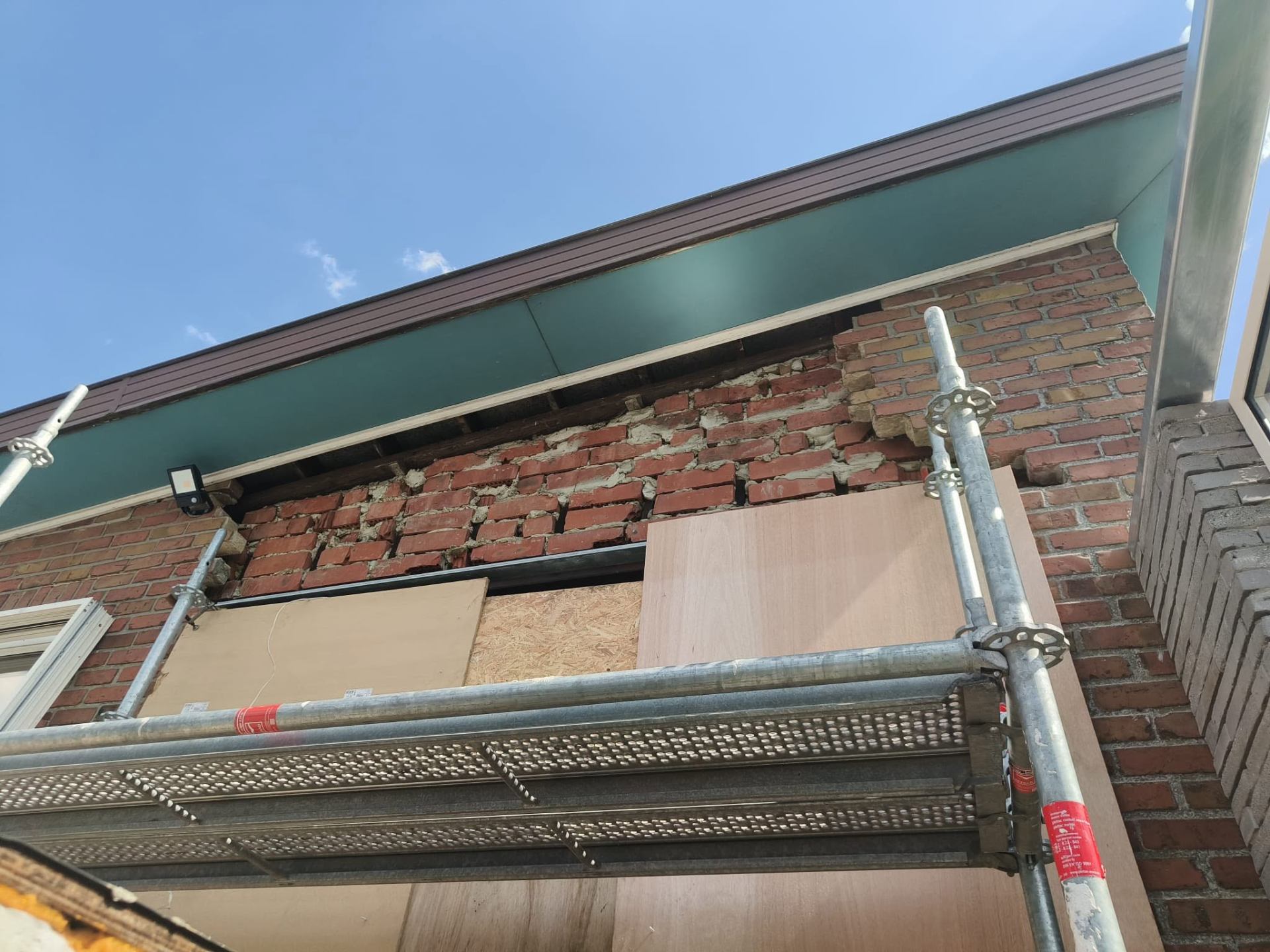 Beschadigd metselwerk onder dakgoot vóór herstel — losse stenen en open voegen