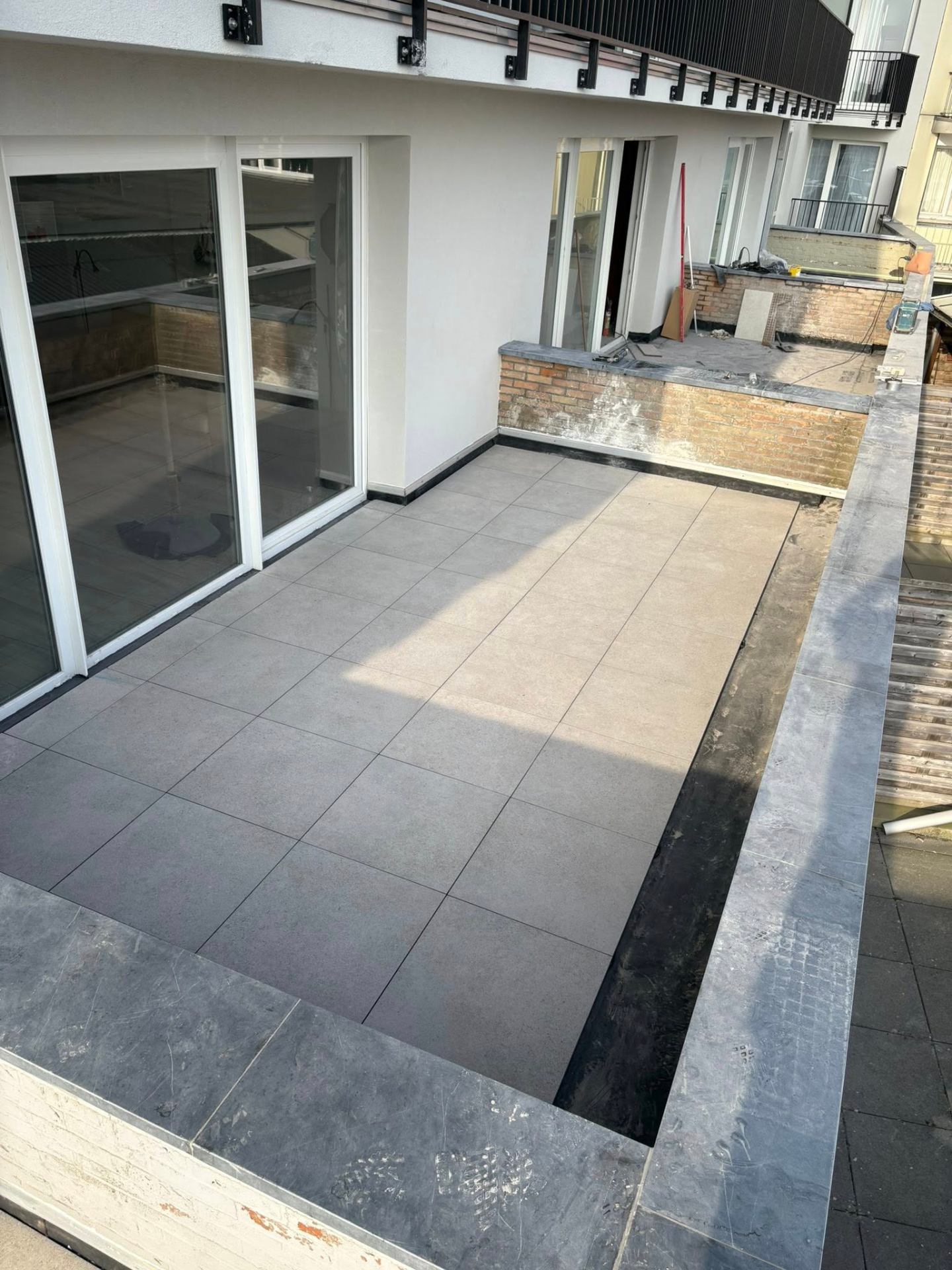 Volledig afgewerkt terras met grijze keramische tegels