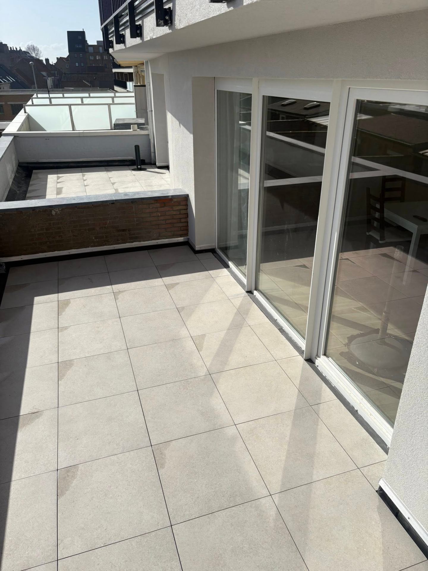 Vernieuwd terras met lichte keramische tegels na renovatie